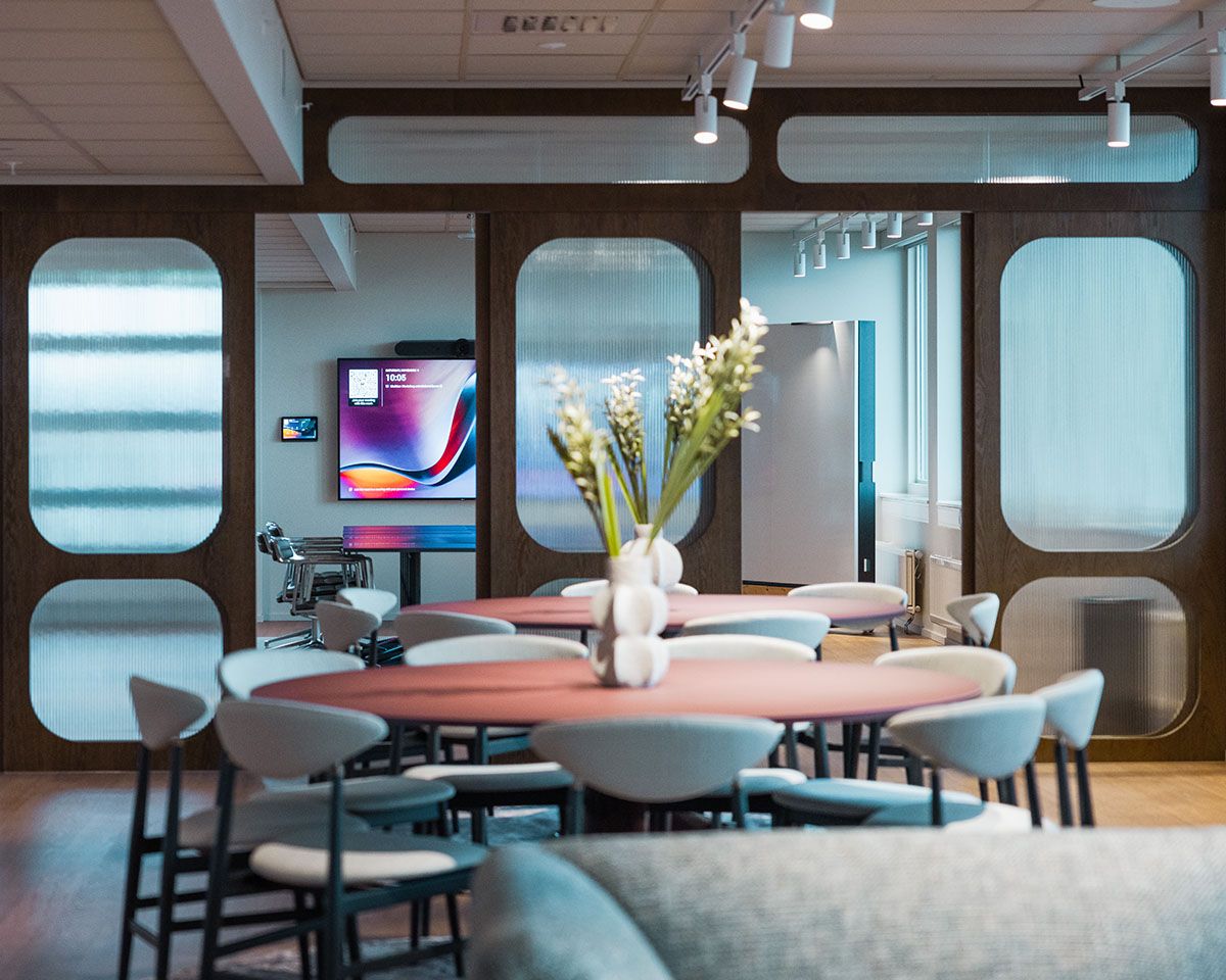 Modern office with seating and a large TV on the back wall.