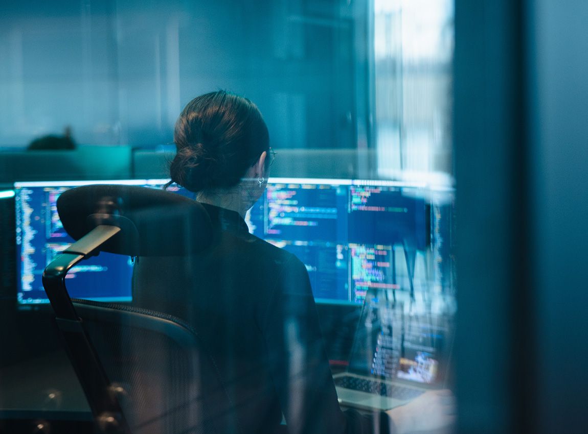 Woman coding, seen through a window. 