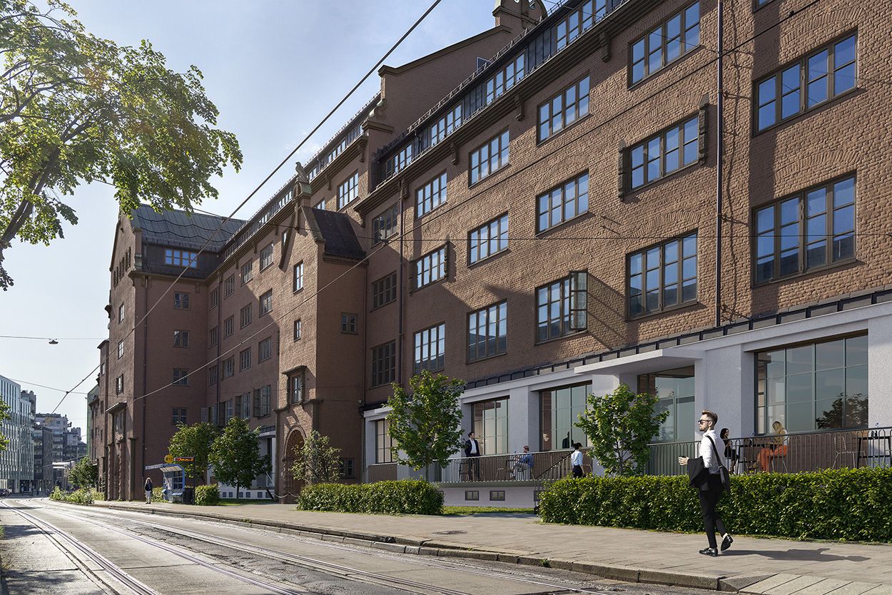 People walking by and sitting outside a renovated brick office building on a sunny city street.